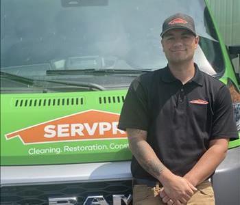 Man with dark hair leaning on Green SERVPRO® truck to pose for photo