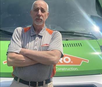 Man crossing arms posing on Green SERVPRO® truck for photo