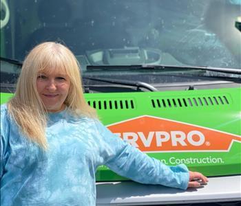 Woman leaning on Green SERVPRO® truck to pose for photo