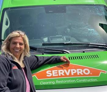 Office Manager leans on green SERVPRO® truck to pose for picture